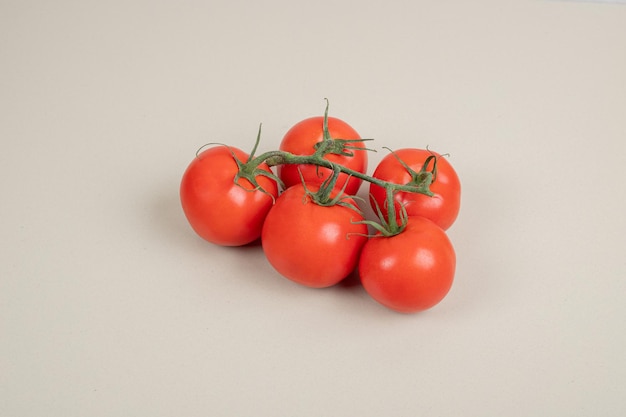 흰색 테이블에 녹색 줄기와 신선한, 빨간 토마토의 무리.