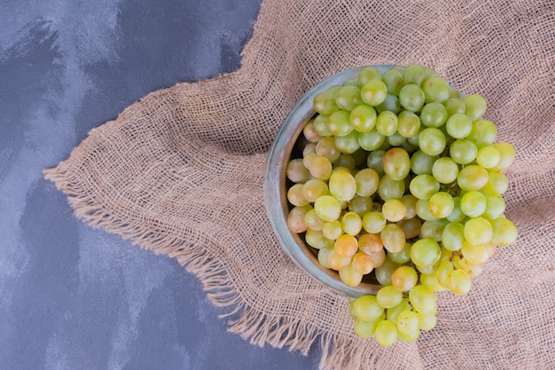 Бесплатное фото Гроздь зеленого винограда в блюде на синем.