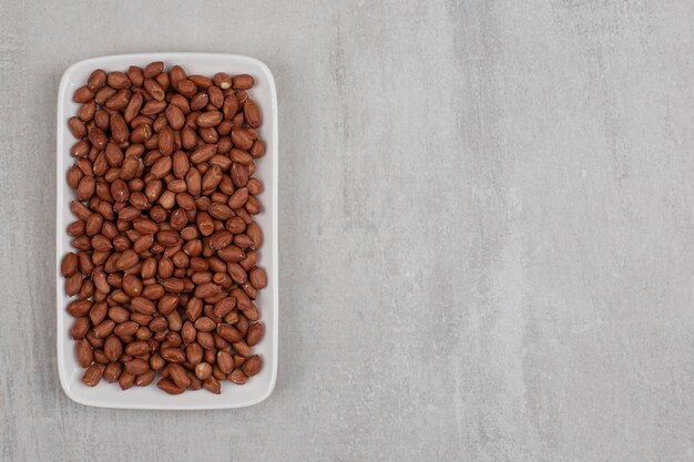 Bunch of organic peanuts on white plate.