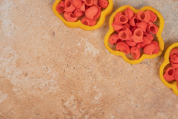 Bunch of pasta in bell pepper slices on orange background