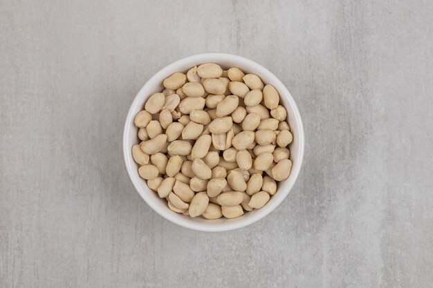 Bunch of peeled peanuts in white bowl.