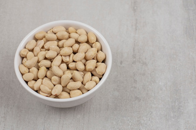 Bunch of peeled peanuts in white bowl.