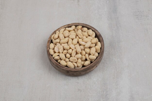 Bunch of peeled peanuts in wooden bowl.