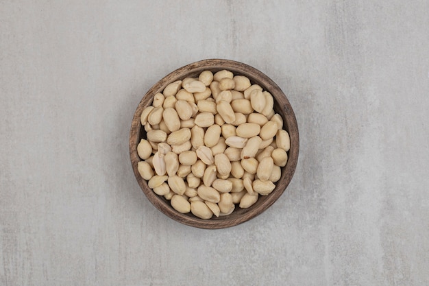 Bunch of peeled peanuts in wooden bowl.