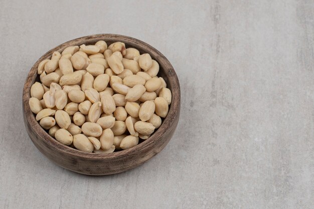 Bunch of peeled peanuts in wooden bowl.