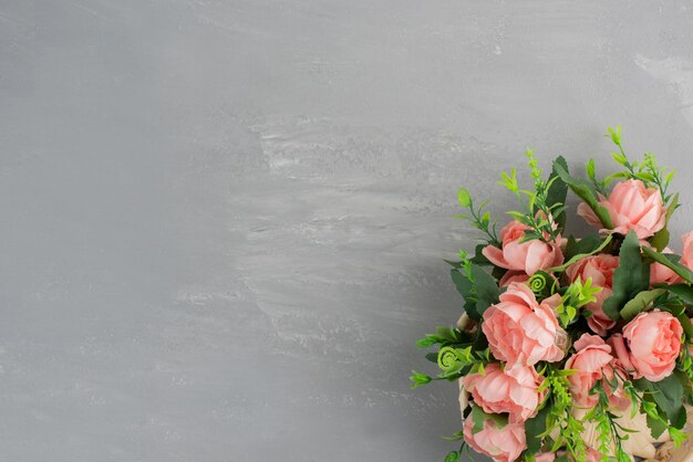 Bunch of pink roses with leaves on grey surface