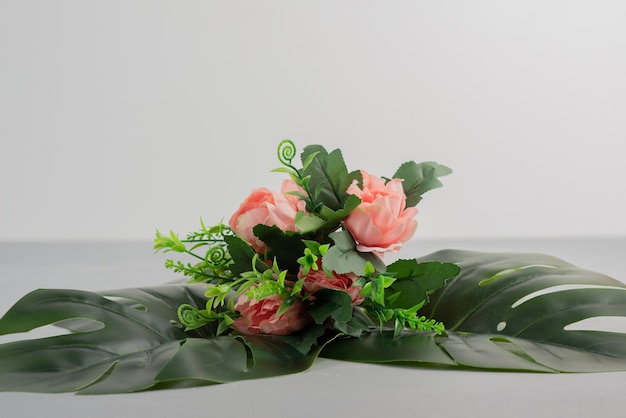 Bunch of pink roses with leaves on grey surface