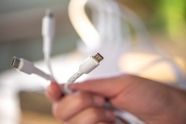 A bunch of plugs for different types of charging connectors in white. Diverse plugs in hand close-up.