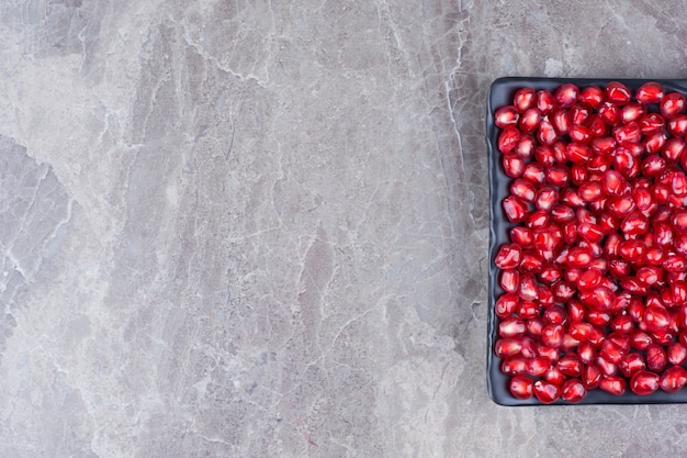 Bunch of pomegranate seeds on black plate. 