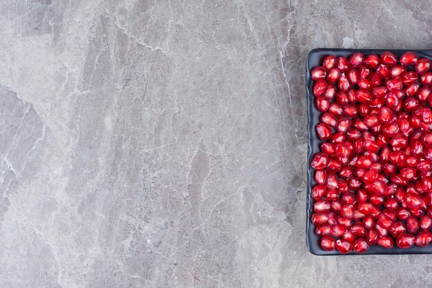 Bunch of pomegranate seeds on black plate. 