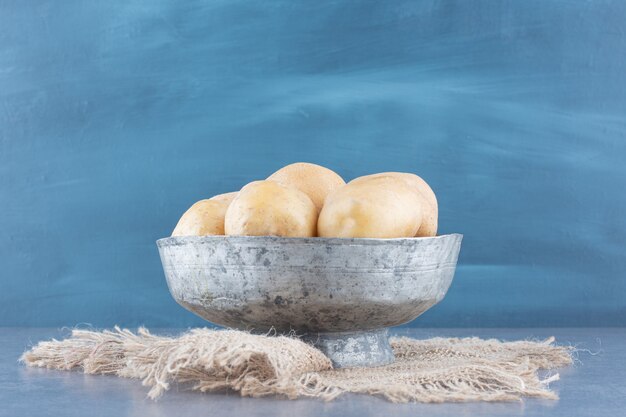 Bunch of potatoes in metal mug with burlap.