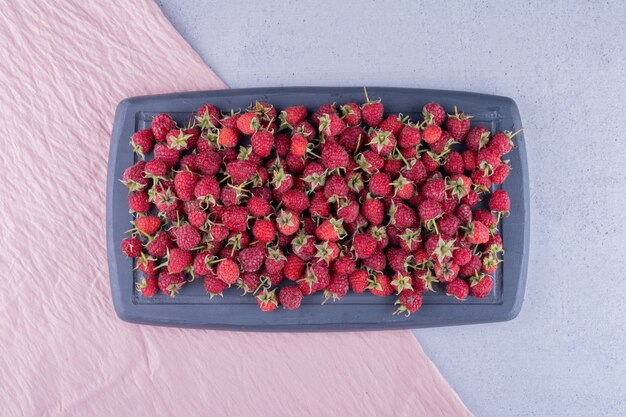 Bunch of raspberries on a navy board on marble background. High quality photo