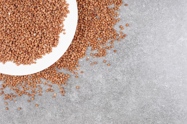 Bunch of raw buckwheat on white plate