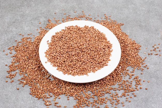 Bunch of raw buckwheat on white plate