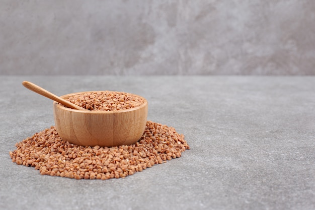 Bunch of raw buckwheat in wooden bowl