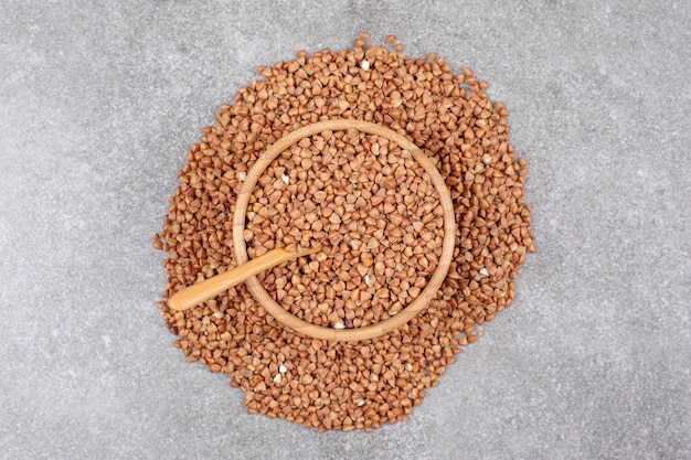 Bunch of raw buckwheat in wooden bowl