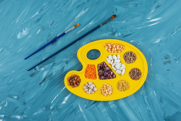 Bunch of raw dry beans placed inside of painting palette.