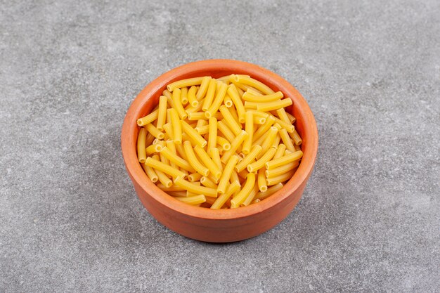 Bunch of raw macaroni in wooden bowl