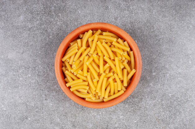 Bunch of raw macaroni in wooden bowl