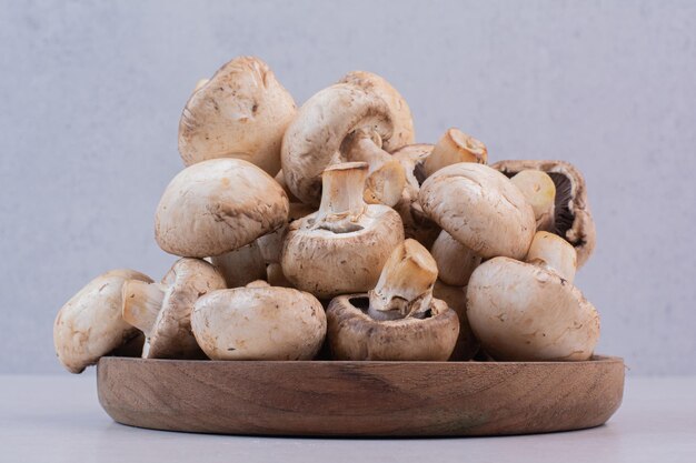 Bunch of raw mushrooms on wooden plate.