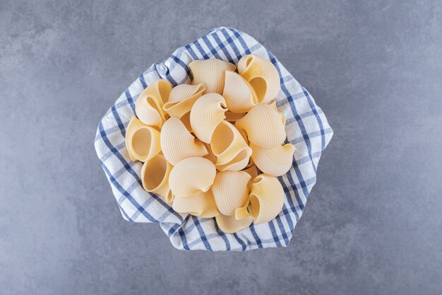 木製のバケツに生のシェルパスタの束。