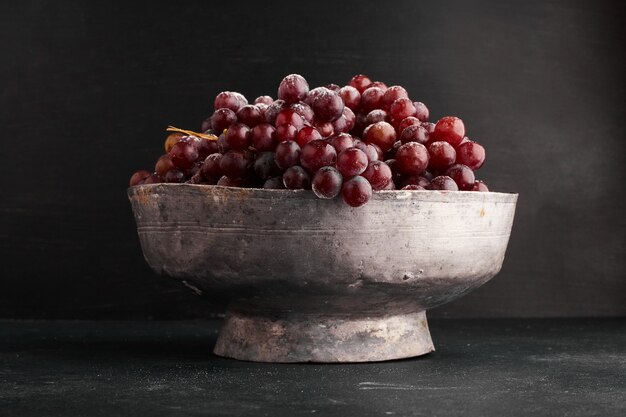 A bunch of red grapes in a metallic bowl. 