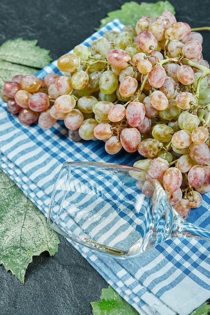 Un grappolo d'uva rossa e un bicchiere di vino sulla tovaglia blu. foto di alta qualità