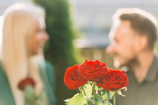 Free photo bunch of red roses in front of couple looking at each other