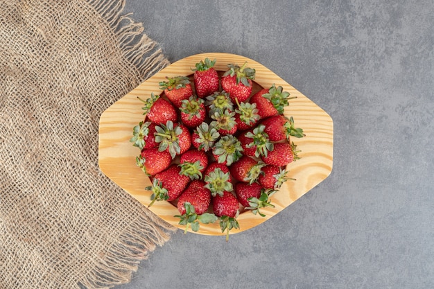 Bunch of red strawberries on wooden plate. High quality photo