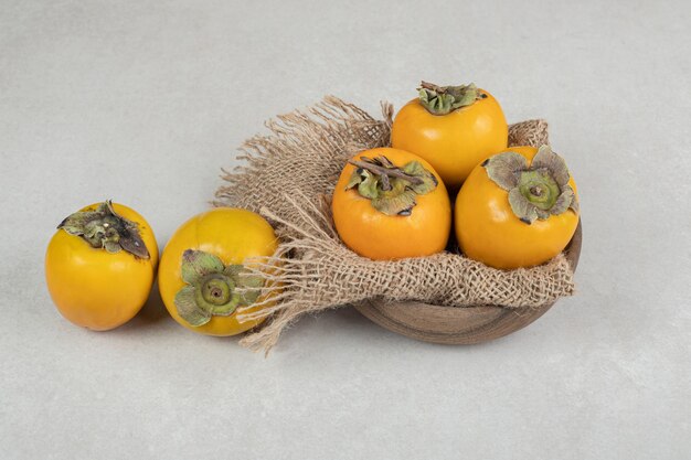 Bunch of ripe delicious persimmons in wooden bowl