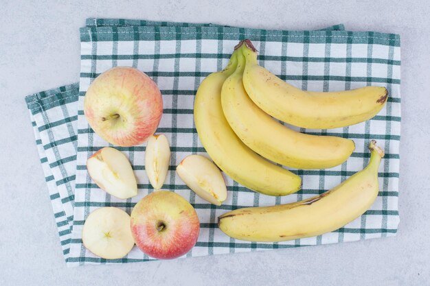 テーブルクロスにスライスしたリンゴと熟したフルーツバナナの束。高品質の写真