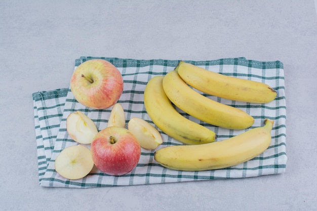 Bunch of ripe fruit bananas with sliced apple on tablecloth. High quality photo