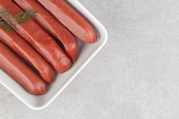 Bunch of smoked sausages on white plate.