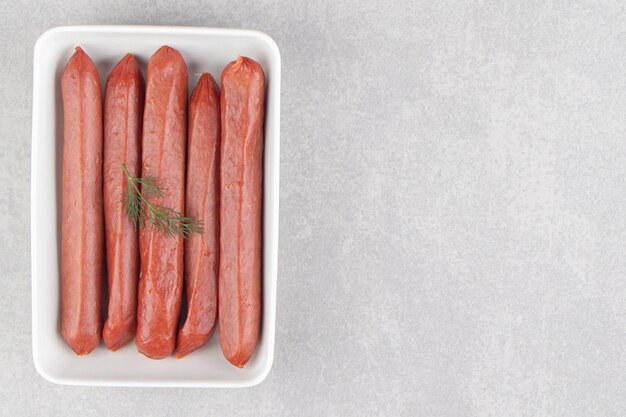 Bunch of smoked sausages on white plate.