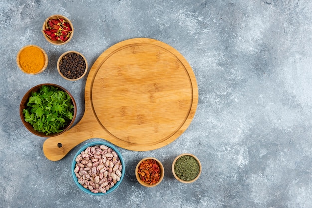 Bunch of spices and bowl of beans on marble background.