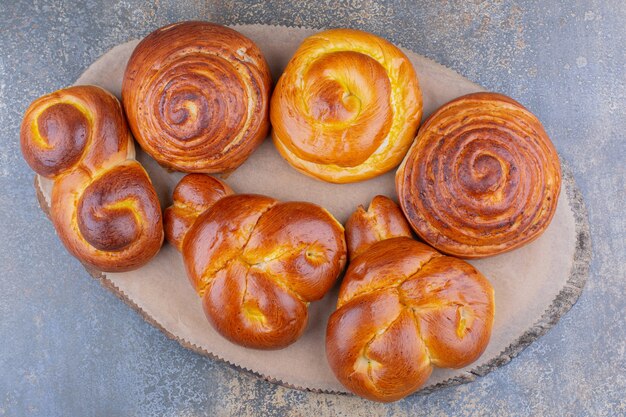 Bunch of sweet buns on a wooden board on marble surface