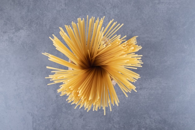 Bunch of uncooked dry spaghetti in vase.