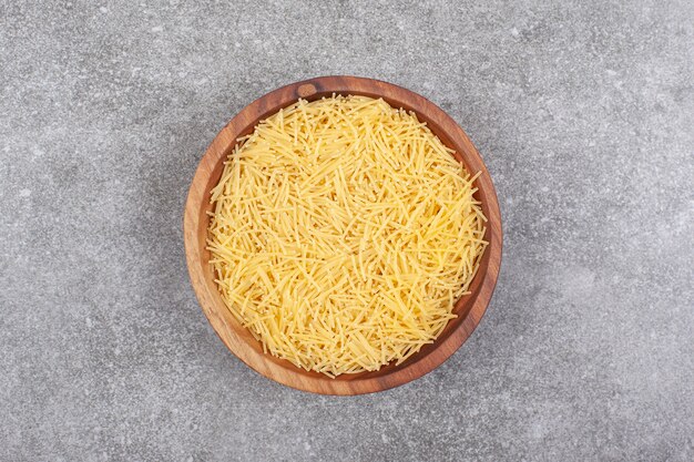 Bunch of uncooked pasta in wooden bowl