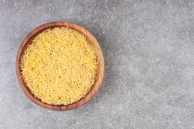 Bunch of uncooked pasta in wooden bowl