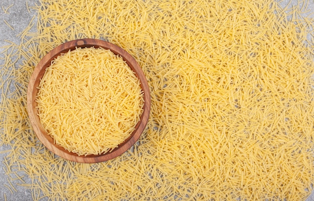 Bunch of uncooked pasta in wooden bowl