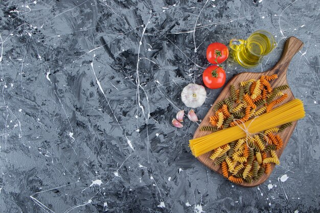 Bunch of uncooked spaghetti in rope with multi colored pasta and vegetables. 