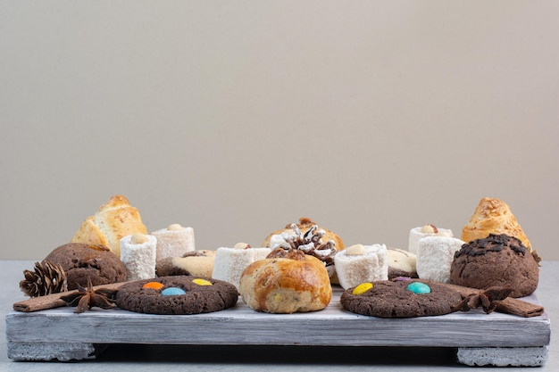 Bunch of various cookies on wooden board with pinecones. High quality photo