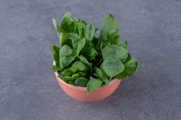 Bunch watercress in bucket, on the marble surface.