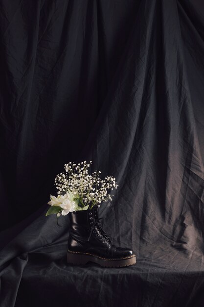 Букет белых цветов в темном кожаном ботинке