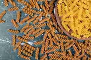 Foto gratuita mazzo di pasta fusilli giallo e marrone su sfondo blu. foto di alta qualità