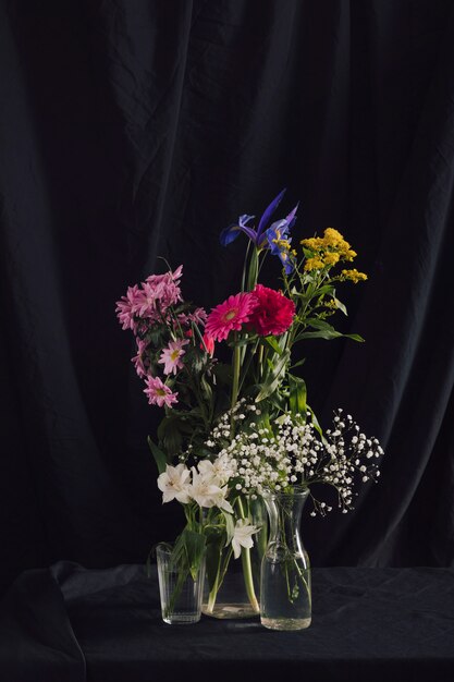 Bunches of colourful flowers in vases with water