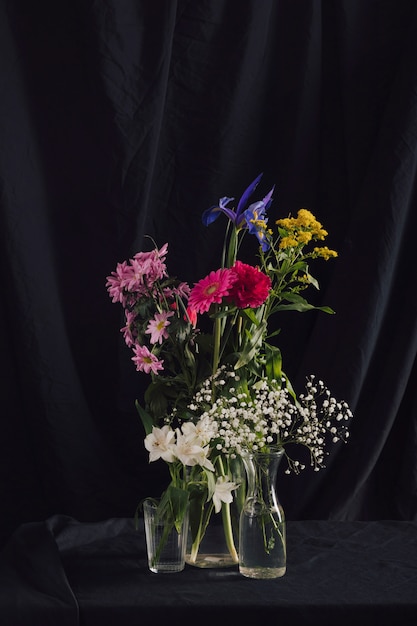 Bunches of colourful flowers in vases with water