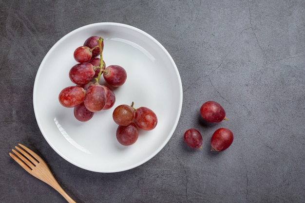 Foto gratuita grappoli di uva rossa matura fresca sulla superficie scura.