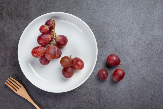 Bunches of fresh ripe red grapes on the dark surface.