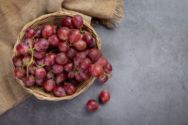 Грозди свежего спелого красного винограда на темной поверхности.